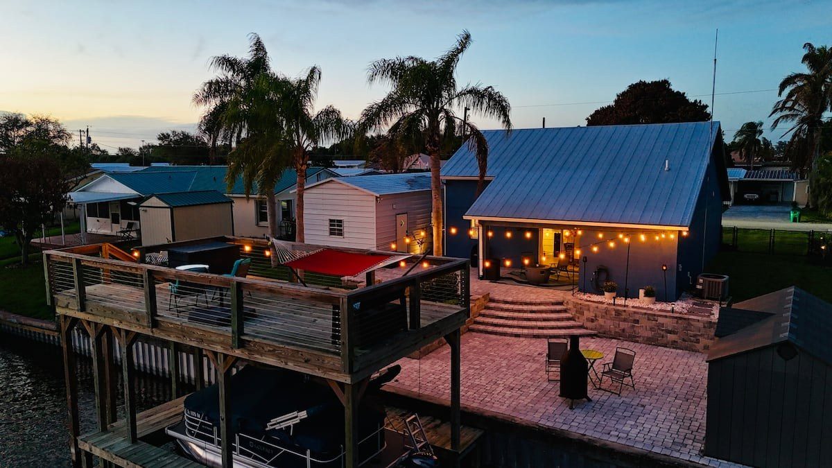 Taylor Creek Cottage at dusk: string lights over the patio and the deck above the canal