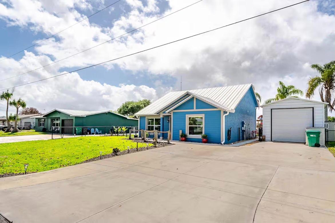 Front of the blue cottage with a metal roof, wide driveway and garage